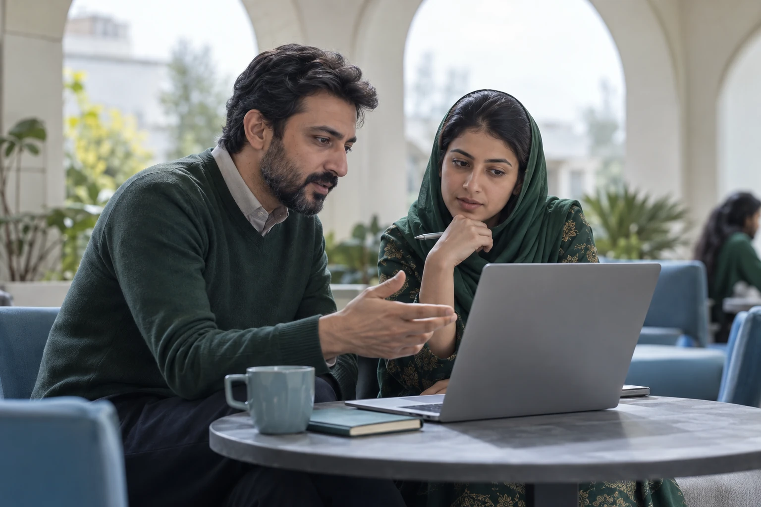 Illustrative scene: Two people discussing information together on a laptop.